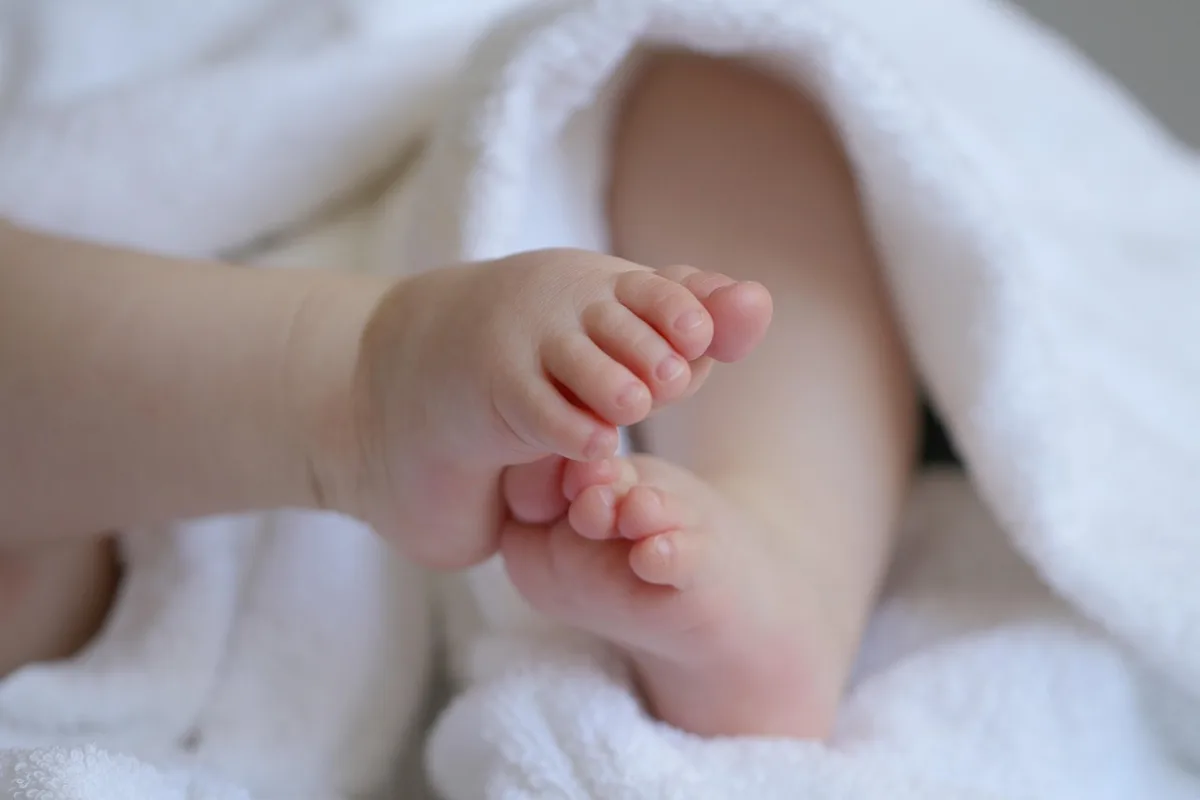 Vêtements de bébé empilés et un lange sur une table à langer en lumière du jour