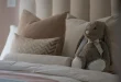 Pile de pyjamas en fibres naturelles sur un lit lumineux, mains touchant le tissu