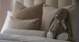 Pile de pyjamas en fibres naturelles sur un lit lumineux, mains touchant le tissu