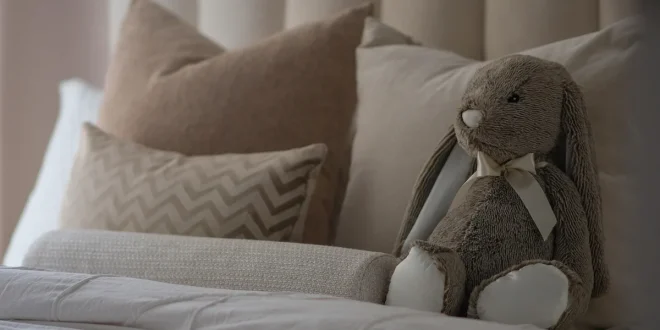 Pile de pyjamas en fibres naturelles sur un lit lumineux, mains touchant le tissu