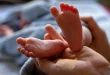 Parent habille un bébé en couches légères près d'une table à langer, lumière naturelle