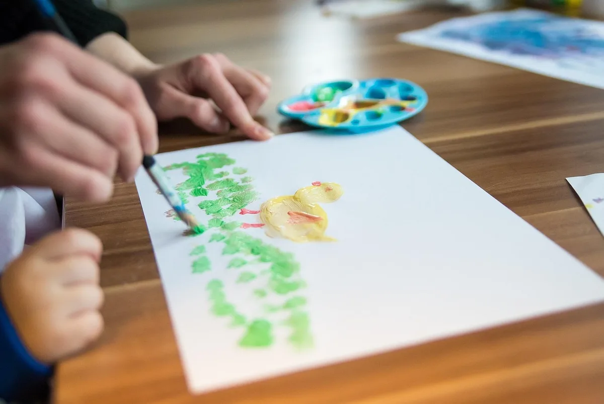 Enfant dessinant avec un kit créatif sur une table bien éclairée