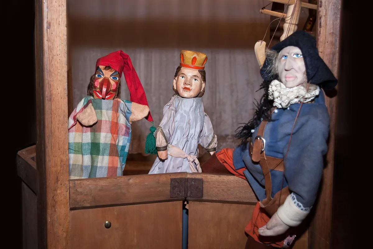 Parent et enfant jouant au théâtre de marionnettes dans un salon lumineux