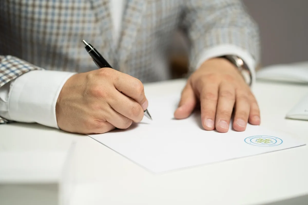 Main tenant une pièce d'identité à côté d'un formulaire en ligne sur un écran
