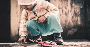 Coin d'une salle de jeu en plein jour avec jouets variés et une main d'adulte tendue