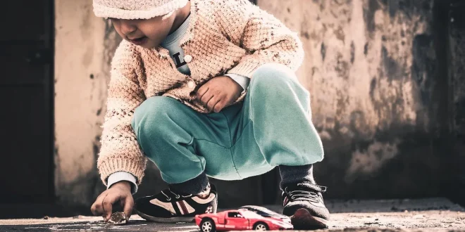 Coin d'une salle de jeu en plein jour avec jouets variés et une main d'adulte tendue