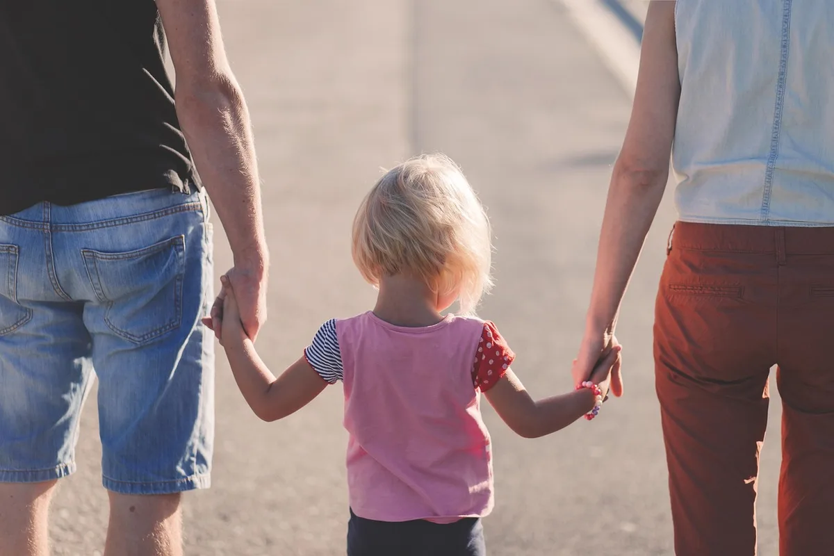 Parent lisant calmement à voix posée à côté d'un enfant au lit