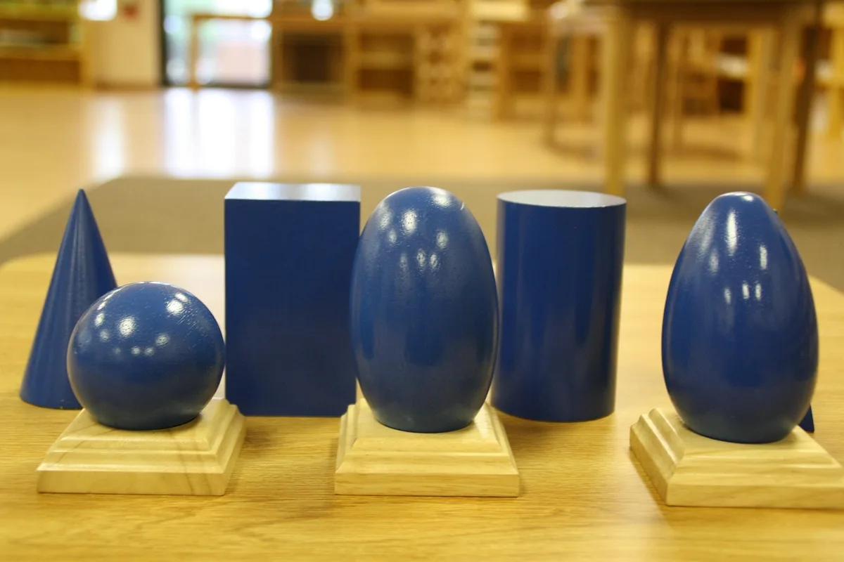 Étagères basses avec matériel Montessori en bois dans une classe lumineuse