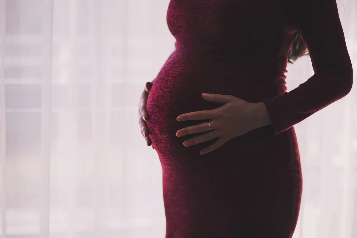 Femme enceinte tenant le bas-ventre, illustrant un tiraillement pelvien
