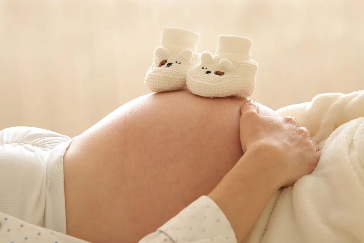 Main posée sur un certificat médical de grossesse sur un bureau