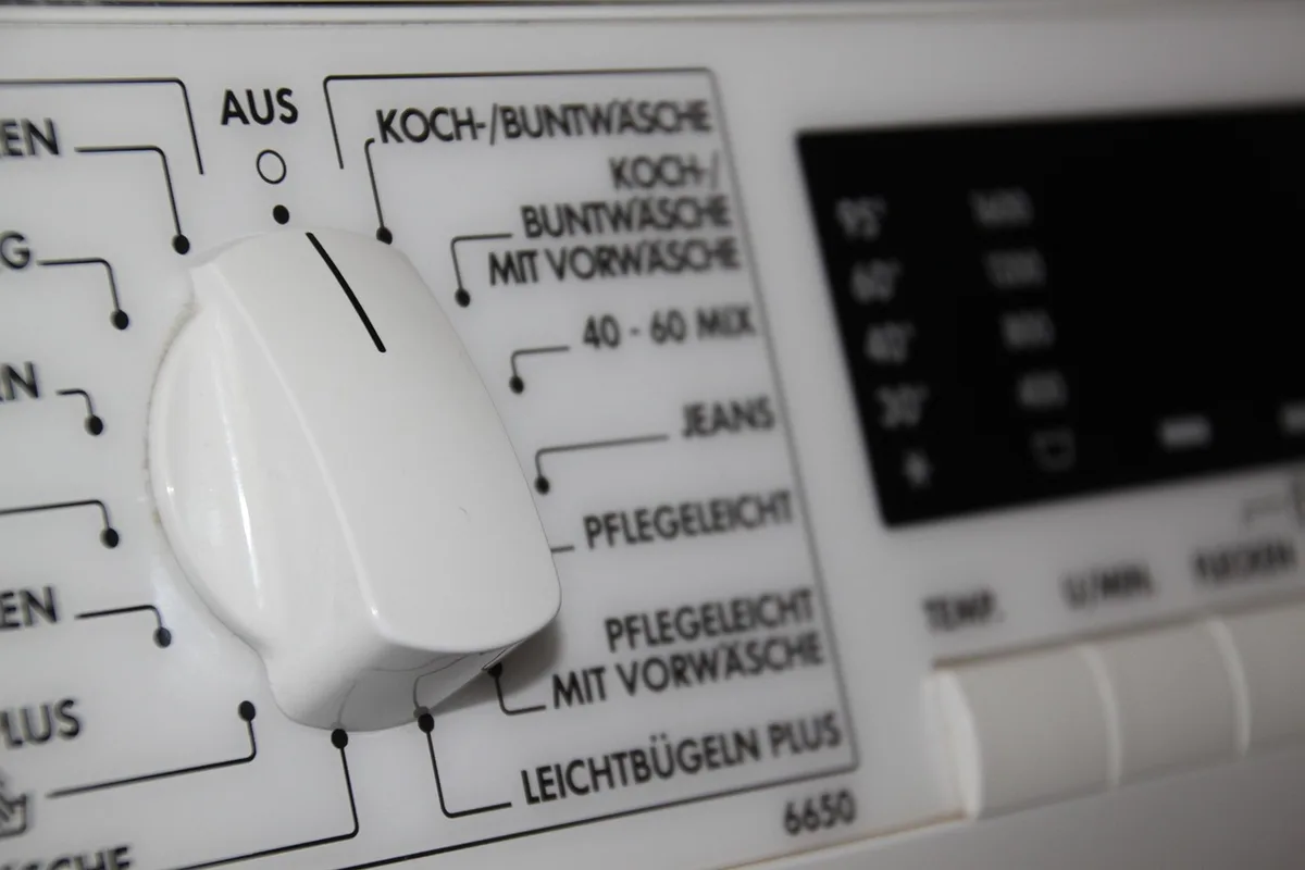 Petits vêtements de bébé retournés dans un filet de lavage près d'une machine