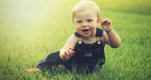Petits vêtements de bébé pliés près d'une fenêtre baignés de lumière naturelle