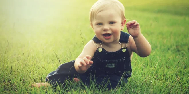 Petits vêtements de bébé pliés près d'une fenêtre baignés de lumière naturelle
